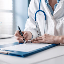 médecin assis à son bureau rédige une prescription sur ordonnance.